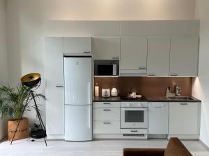 cocina con armarios blancos y nevera en Cozy Design Loft next to Metro en Helsinki