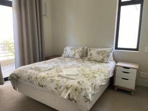 a bedroom with a bed and a nightstand and a window at The Herolds Bay 611 in Herolds Bay