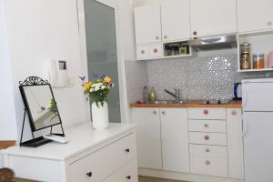 a kitchen with white cabinets and flowers in a mirror at Apartment in the heart of Ljubljana in Ljubljana