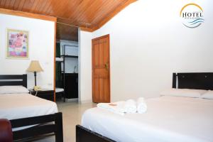 a hotel room with two beds and a door at Hotel Roca & Mar in Santa Marta