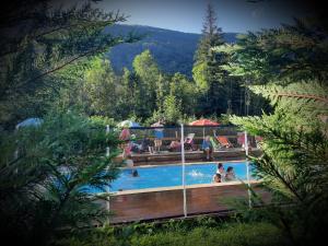 a pool with people in it with people sitting in it at Le Valserine - Camping éco responsable in Chézery-Forens