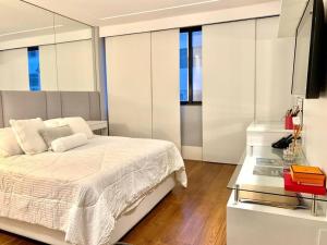 1 dormitorio con 1 cama blanca y TV en Apartamento na quadra da praia en Río de Janeiro