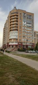 un gran edificio con coches estacionados frente a él en Уютная квартира комфорт класса - 41, en Astana