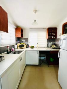 a kitchen with white cabinets and a sink and a refrigerator at КВАРТИРА ВОЗЛЕ МОРЯ! in Haifa