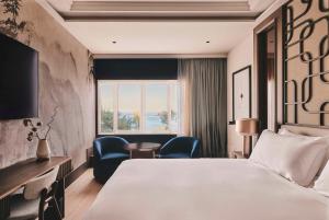 a hotel room with a bed and chairs and a window at Nobu Hotel San Sebastián in Donostia-San Sebastián