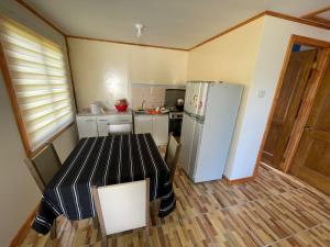 a small kitchen with a table and a refrigerator at cabañas san antonio in Los Ángeles