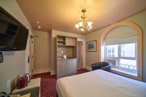 a bedroom with a bed and a television and a kitchen at The Bedford Regency Hotel in Victoria +37 photos