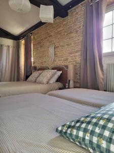 a bedroom with two beds and a brick wall at Le Clos du Botaniste in Pouilly-le-Monial