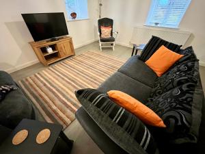 29 Malthouse Alnwick Holiday Apartment في ألنويك: غرفة معيشة مع أريكة وتلفزيون بشاشة مسطحة