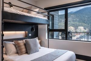 een slaapkamer met een stapelbed en een groot raam bij Altitude Adjustment by Revelstoke Vacations in Revelstoke