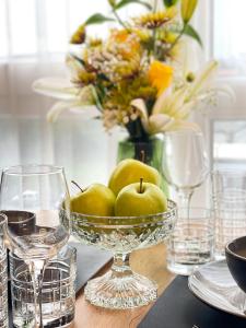una ciotola di mele su un tavolo con bicchieri e fiori di Emerald Apartment a Arad
