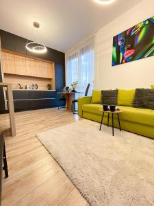 Emerald Apartment في أراد: غرفة معيشة مع أريكة صفراء ومطبخ