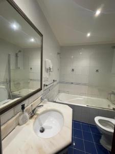 ein Badezimmer mit einem Waschbecken, einer Badewanne und einem Spiegel in der Unterkunft Fun Beach - Durrat AL Arous in Durrat Al-Arus