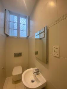 La salle de bains est pourvue d'un lavabo, de toilettes et d'une fenêtre. dans l'établissement SeaView Valletta Apartment, à La Valette