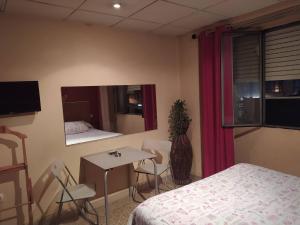 a room with a bed and a table and a mirror at Hostal Happystay in Valencia