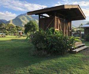 a small wooden building with a hill in the background at Explore Maui's diverse campgrounds and uncover the island's beauty from fresh perspectives every day as you journey with Aloha Glamp's great jeep equipped with a rooftop tent in Paia