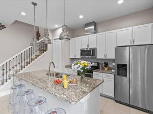 a kitchen with white cabinets and a stainless steel refrigerator at LOCATION!! Modern Luxury Home 2 miles from Disney! in Orlando