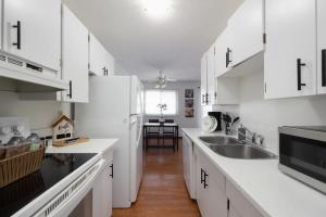 a white kitchen with white cabinets and a sink at Newly Renovated 2BR with Parking and Near NLRHC in Fort McMurray