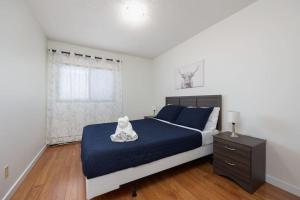 ein Schlafzimmer mit einem Bett mit einer blauen Decke und einem Fenster in der Unterkunft Newly Renovated 2BR with Parking and Near NLRHC in Fort McMurray