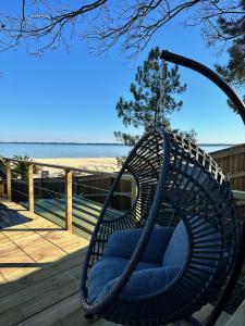 une chaise en osier assise sur une terrasse près de la plage dans l'établissement Chalet et Jaccuzy sur la plage, à Biscarrosse