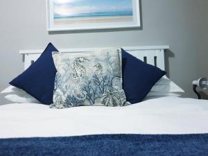 ein Bett mit blauen Kissen und einem Kissen darauf in der Unterkunft VillaMed Guesthouse in Klerksdorp