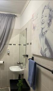 ein Badezimmer mit einem Waschbecken und ein Bild einer Frau in der Unterkunft VillaMed Guesthouse in Klerksdorp