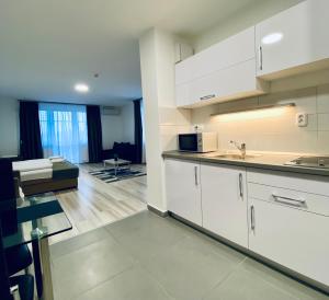 a kitchen with white cabinets and a living room at M&F Apartman in Egerszalók