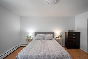 um quarto com uma cama com duas mesas de cabeceira e uma cómoda em Downtown 1BR Top Floor with View Free Parking em Fort McMurray