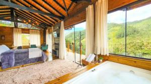 - une chambre avec un lit et une baignoire devant une fenêtre dans l'établissement Chalé Canto da Montanha, à Annitapolis