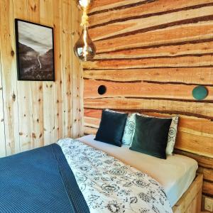 a bed in a room with a wooden wall at La Cabane d'Ode in Sainte-Ode