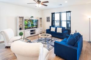 a living room with two blue chairs and a tv at Heads or Tails - LSU in Baton Rouge