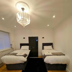 a bedroom with two beds and a chandelier at jAH LODGE BRSITOL BIG HOUSE STAY FREE PARKING 20 PERCENT OFF WEEKLY MONTHLY STAY BUSINESS CONTRACTOR STUDENTS RELOCATIONS 5BED in Bristol