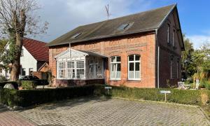 a brick house with a large window on a street at Ferienwohnung Rosenholz in Butjadingen
