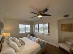 a bedroom with a bed with a ceiling fan and a chair at Melbourne Beach Resort in Melbourne Beach