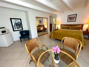 a bedroom with a bed and two wicker chairs at Vista Grande Resort - A Gay Men's Resort in Palm Springs