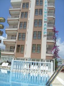 a hotel with a swimming pool in front of a building at Palmen Apart Hotel in Alanya