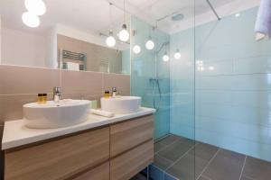 a bathroom with two sinks and a glass shower at Sunny Hotel Home with An Unbeatable Balcony View in Budapest