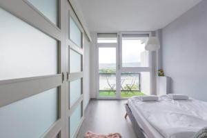 a bedroom with a bed and a large window at Sunny Hotel Home with An Unbeatable Balcony View in Budapest