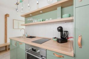 a kitchen with green cabinets and a counter top at Sunny Hotel Home with An Unbeatable Balcony View in Budapest