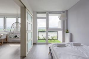 a bedroom with a bed and a room with windows at Sunny Hotel Home with An Unbeatable Balcony View in Budapest