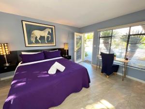 a bedroom with a purple bed with a horse painting on the wall at Vista Grande Resort - A Gay Men's Resort in Palm Springs