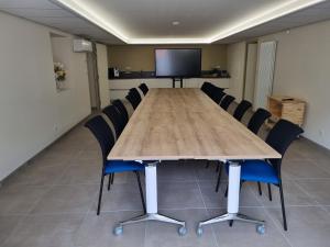 una sala de conferencias con una gran mesa de madera y sillas en Logis hôtel restaurant les Carillons, en Cransac