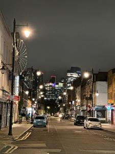 una strada di città di notte con auto parcheggiate sulla strada di Hoxton Street, Shoreditch a Londra
