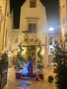 osoba stojąca przed domem z lampkami świątecznymi w obiekcie trulli mancinella w mieście Locorotondo