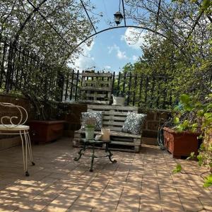 a patio with a chair and a bench in a garden at B&B Le Chicche di Lulu' in Borghetto
