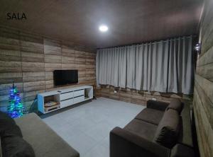 ein Wohnzimmer mit einem Sofa, einem TV und einem Weihnachtsbaum in der Unterkunft Apartamento com três suítes em Garanhuns próximo ao Parque Euclides Dourado in Garanhuns