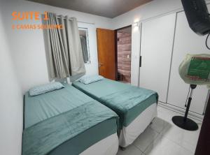 - une chambre avec 2 lits jumeaux et une lampe dans l'établissement Apartamento com três suítes em Garanhuns próximo ao Parque Euclides Dourado, à Garanhuns