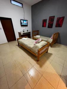 Zimmer mit 2 Betten und einem TV an der Wand in der Unterkunft Angelina Pilar Córdoba in Pilar