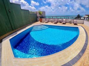 a swimming pool with chairs and the ocean in the background at Natal Plaza in Natal
