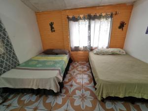 JujutlaにあるRancho Las Mercedesのタイルフロアの客室で、ベッド2台が備わります。